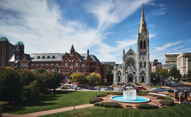 DuBourg Hall and Saint Francis Xavier College Church shot from rooftop with a fountain in the foreground.